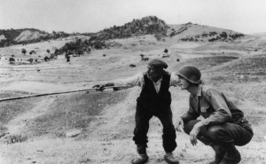 Contadino siciliano indica a un ufficiale americano la direzione presa dai tedeschi, nei pressi di Troina, Sicilia, un celebre scatto di Robert Capa in mostra all'esposizione al Lu.C.C.A. Museum